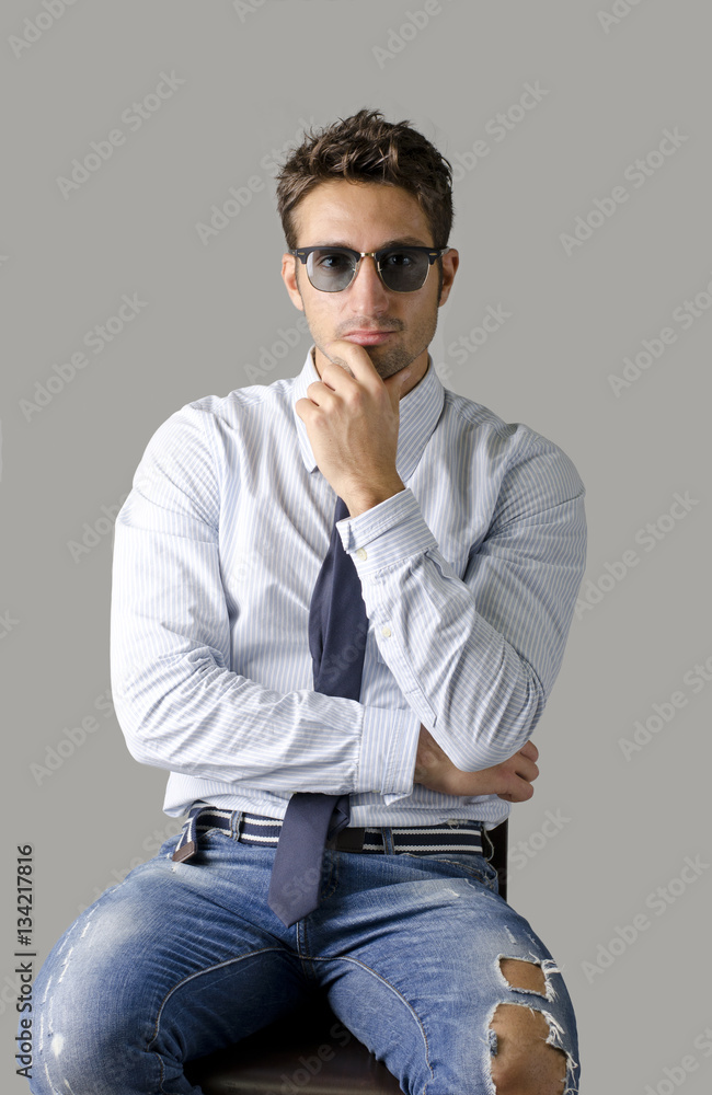 A different kind of young business man wearing shirt, tie and ripped jeans, on light background A different kind of young business man wearing shirt, tie and ripped jeans, on light background