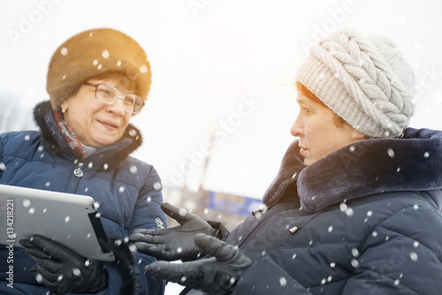 Two elderly women are trying to figure out the plate. They laugh because they do not understand anything. photo