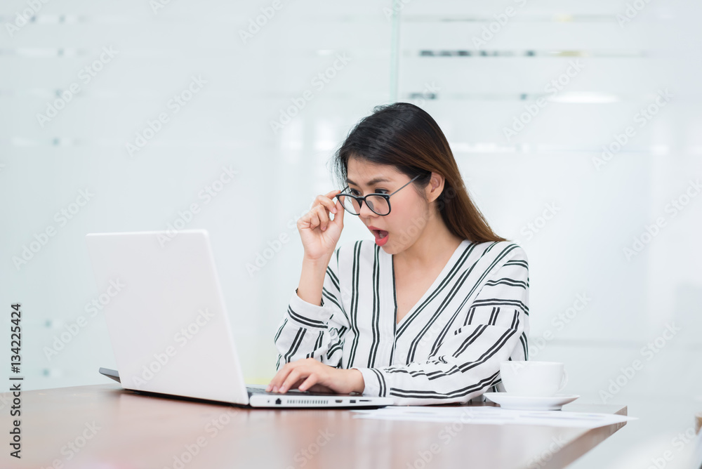Happy beautiful young Asian woman shocked and excited while working with laptop Happy beautiful young Asian woman shocked and excited while working with laptop