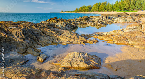 Beautiful seascape with sea, rock and a strip of white sand of Nang Thong Beach, Khao Lak, Thailand. View of bright blue sea with protruding stones. Nature composition.