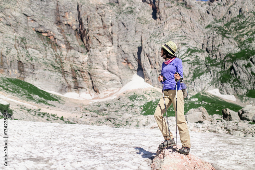 Woman hiker on a glacier in summer mountains