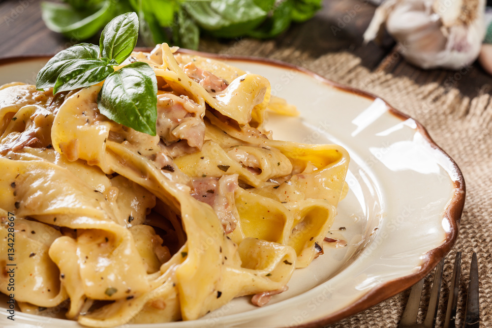 Pappardelle pasta with prosciutto and cheese sauce on a plate Pappardelle pasta with prosciutto and cheese sauce on a plate