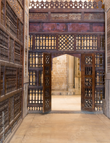 Interleaved wooden wall (mashrabiya) with wooden ornate door in Sultan Qalawun mosque, a historic mosque in Old Cairo, Egypt photo