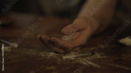 Hand of male opiate addict under influence falling on table, drug abuse problem