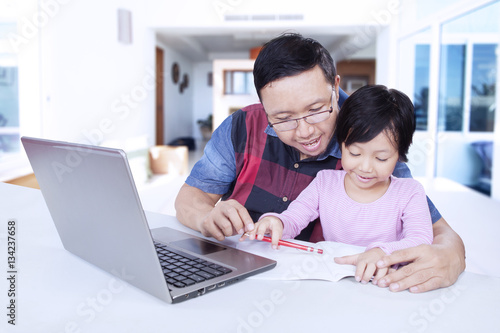 Little girl studying with dad on the table at home