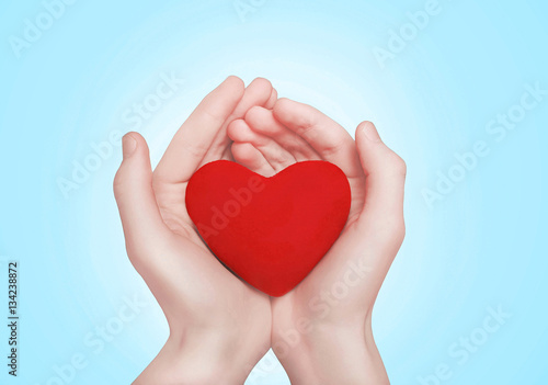 Open hands holding showing red heart over blue background