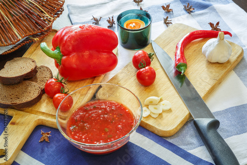 Процесс приготовления томатного соуса аджики и овощи на кухонном столе
