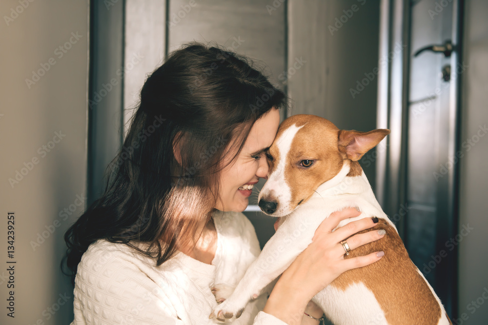 Young beautiful smiling woman hugging her pet - dog at home. Close up portrait. Young beautiful smiling woman hugging her pet - dog at home. Close up portrait.