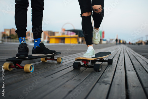 Couple riding longboards on the boardwalk, feet only