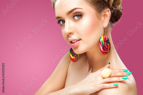 Attractive woman with lollipop in hand on pink background