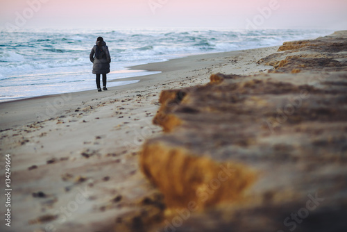 Fotografi Girl walking in the empty beach, sunset time. Baltic sea