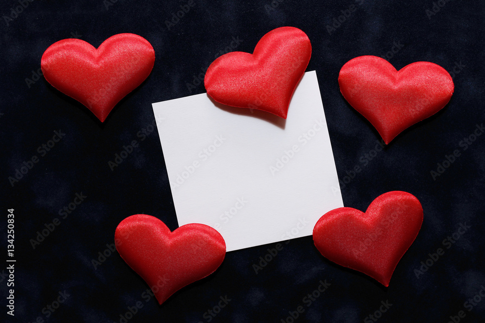 Valentine and several small plush hearts on a blue velvet background.