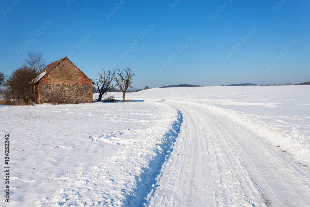 Old abandoned barn in winter. Snow-covered landscape. Rural road in winter. The landscape in the Czech Republic.
