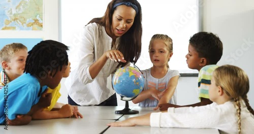 Happy school kids with globe in classroom