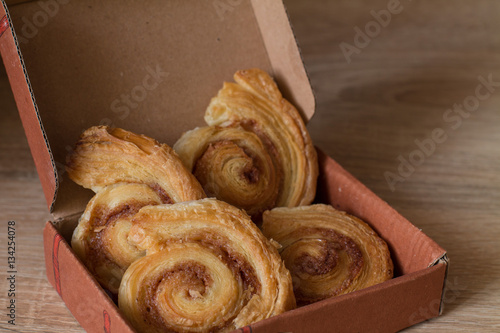 Cinnamon rolls buns in gift box on wood. Christmas surprise.