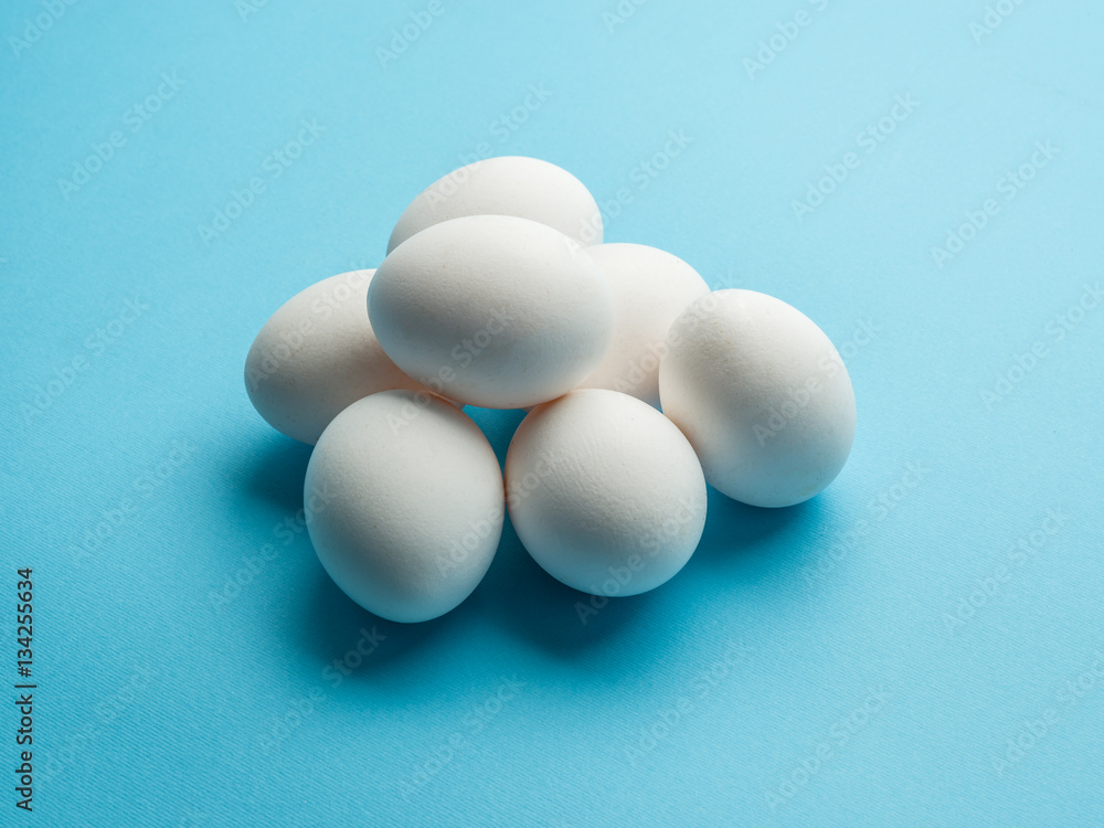 White chicken eggs on the blue background. White chicken eggs on the blue background.