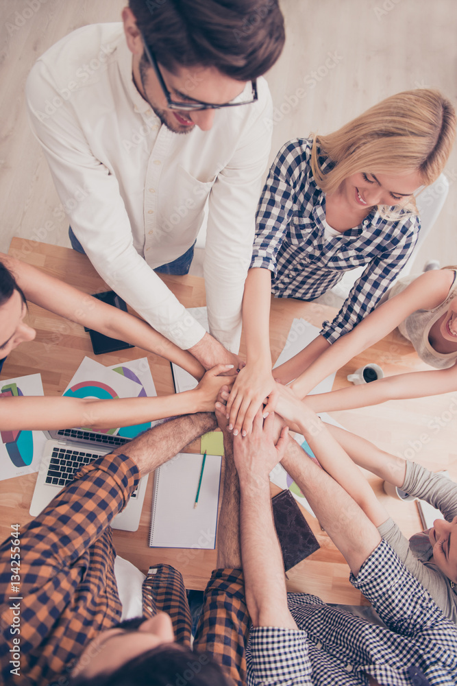 Obraz premium Top view of group of young people holding hands together