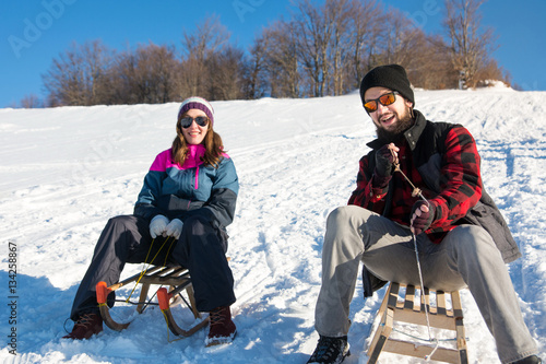Slika na platnu Happy couple sledding down the hill