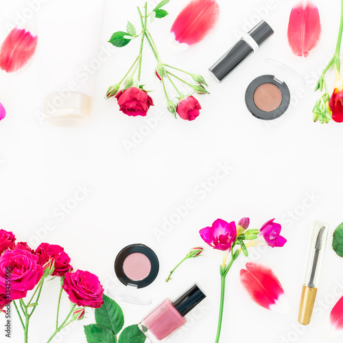 Flat lay, top view. Feminine desk workspace with cosmetics, lipstick, cream and roses on white background.