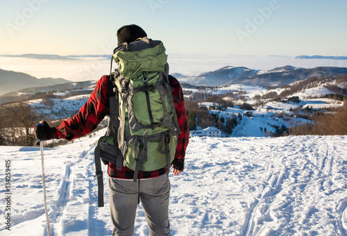 Backpacker hiking on snow covered mountain