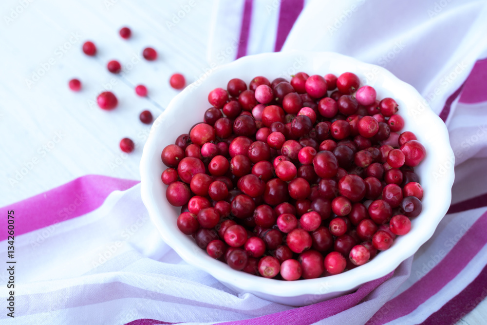 Red cranberry and white plate on pink napkin close up Red cranberry and white plate on pink napkin close up