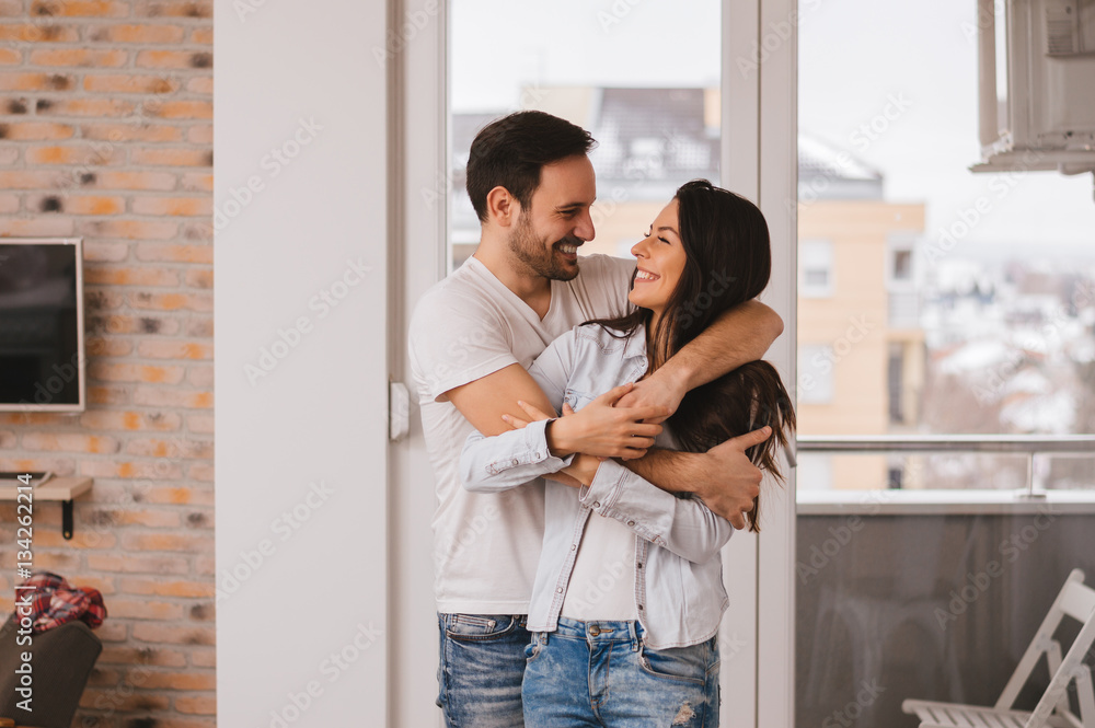 Beautiful young couple hugging in their new appartment.