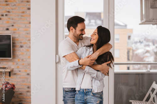 Canvas Print Beautiful young couple hugging in their new appartment.