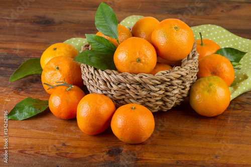 basket of tangerines with green napkin on old wooden background
