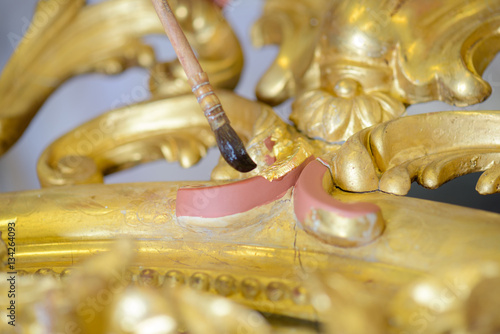 Closeup of paintbrush on gilt frame