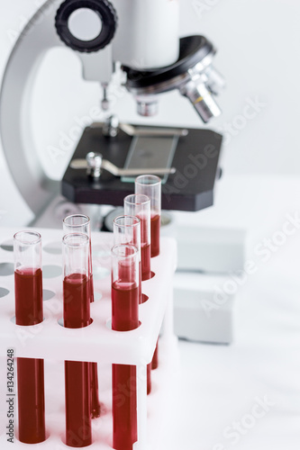 blood in glass tubes on background of microscope