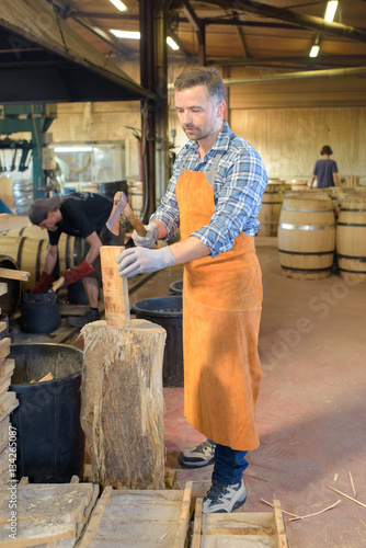 wood barrels production cooper using hammer and tools in workshop