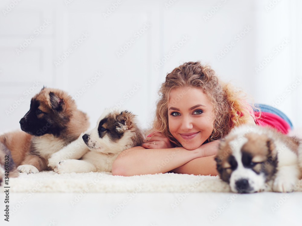 beautiful girl lies on carpet with caucasian shepherd puppies