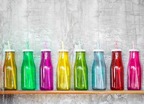 Colorful bottles on the wooden shelf with grey concrete wall background photo