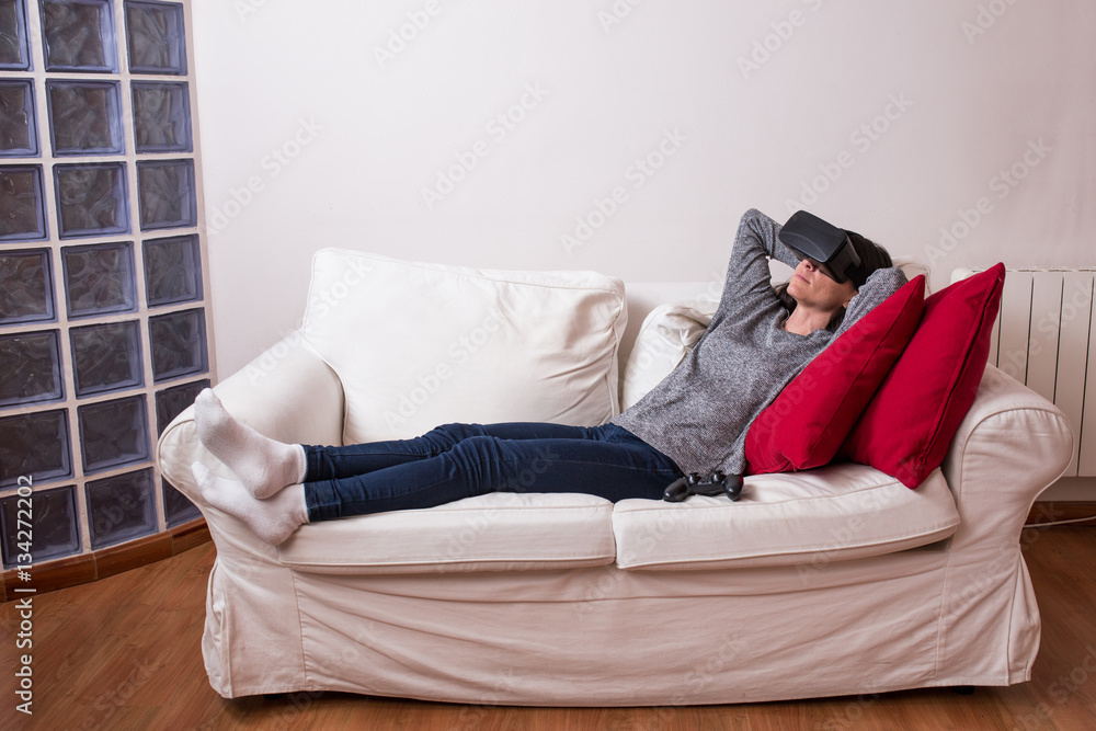 Young woman realxing on the couch and having fun playing a virtu