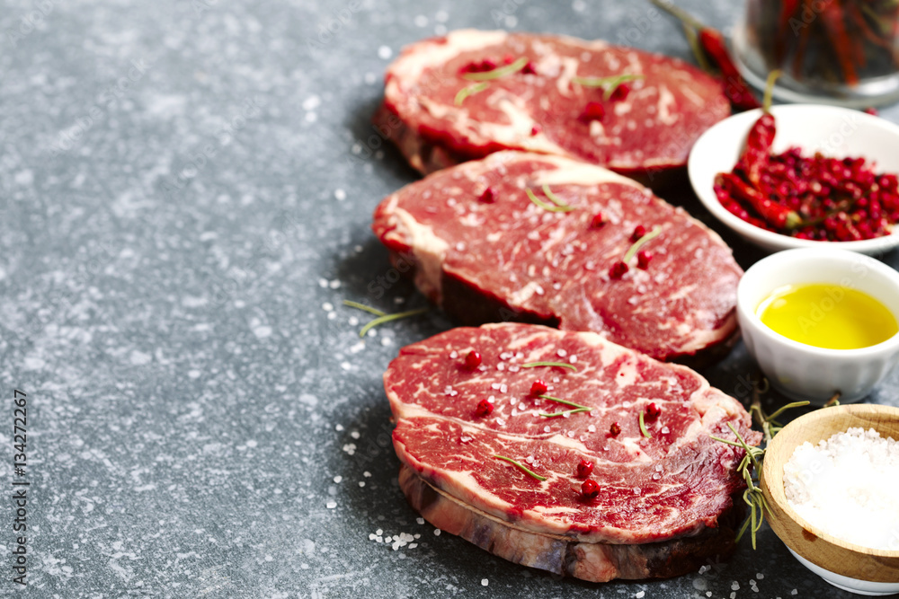 Raw fresh meat Ribeye Steak with rosemary, pepper, salt and olive oil Raw fresh meat Ribeye Steak with rosemary, pepper, salt and olive oil