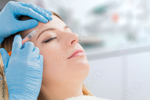 Woman receiving fillers spa facial treatment with syringe