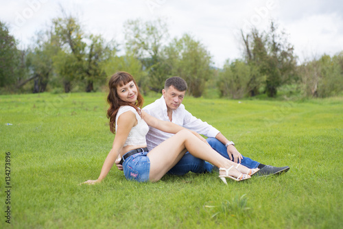 Lovers man and woman sitting on the green grass.