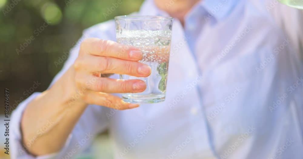 Mid section of senior woman pouring lemonade from a jug Mid section of senior woman pouring lemonade from a jug