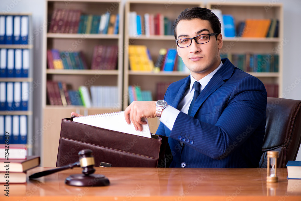 Fototapeta premium Handsome judge with gavel sitting in courtroom