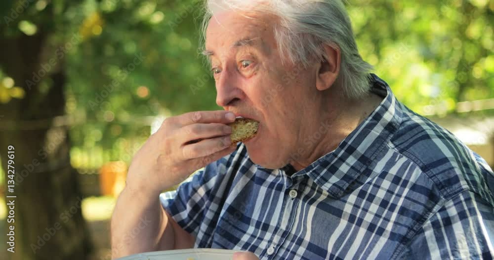Senior man eating sweet food in garden Senior man eating sweet food in garden