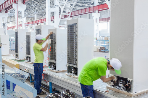 factory floor for production and assembly of household refrigerators on the conveyor belt. factory workers collect refrigerators on the conveyor belt photo
