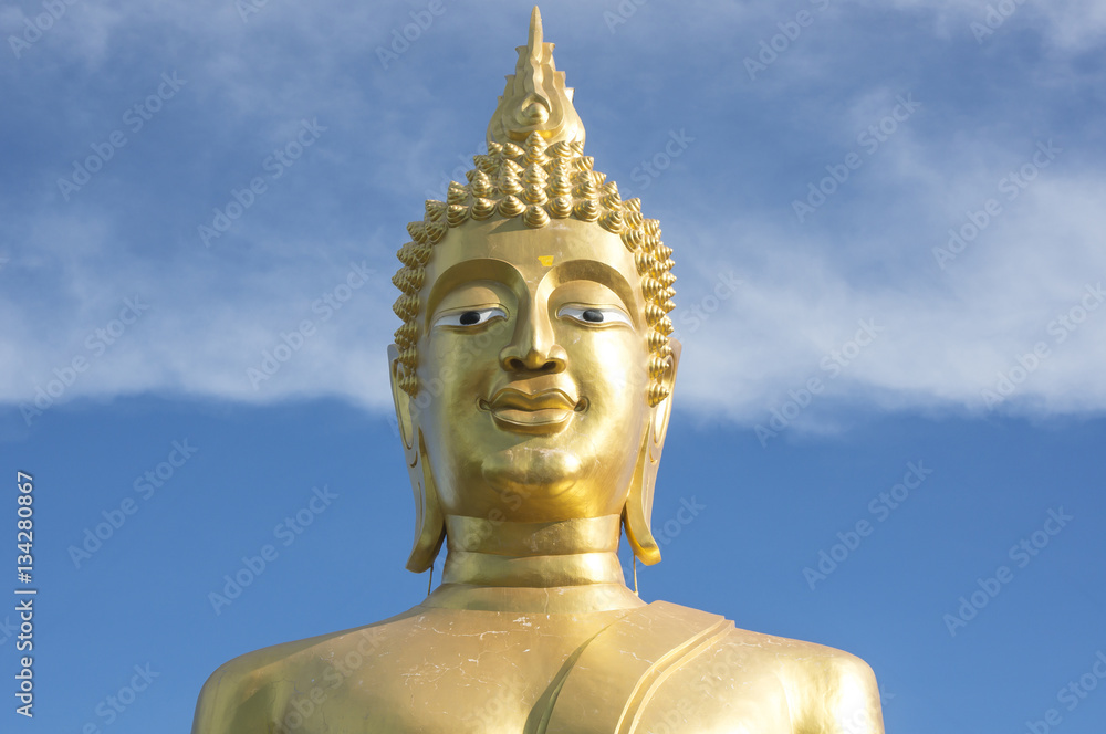 Great Golden Buddha statue in the temple with blue sky and white cloud in Thailand 