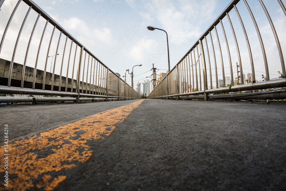 Fototapeta premium Wide angle view of straight yellow line on bitume floor, footbridge, walkway and stairs, perspective with vanishing point, city urban background 