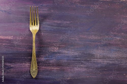 Vintage fork on purple background with copyspace