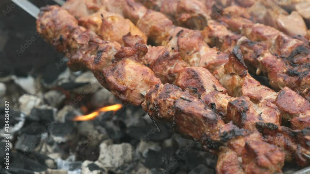 Cooking of pig meat on the metal skewers on coals outdoors. Close up Cooking of pig meat on the metal skewers on coals outdoors. Close up