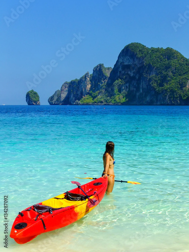 Young woman standing with kayak at Ao Yongkasem beach on Phi Phi