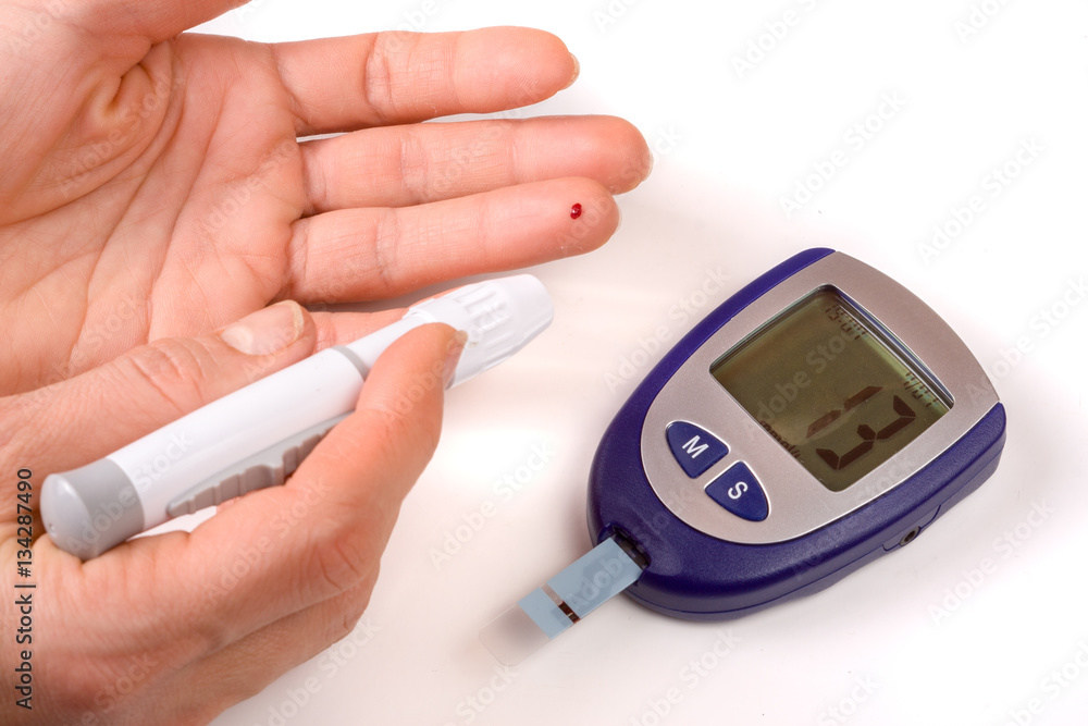 The blood glucose meter with a hand isolated on white background The blood glucose meter with a hand isolated on white background