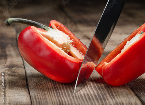 Big kitchen knife cut a bell pepper on wooden table