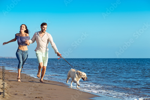 Canvas Print Portrait of a happy couple with dogs at the beach