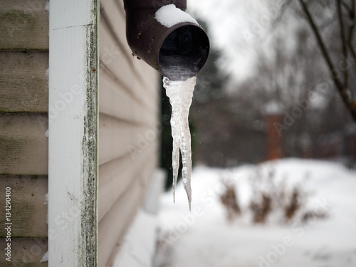 Frozen drain. Large icicles, snow, winter, house corner